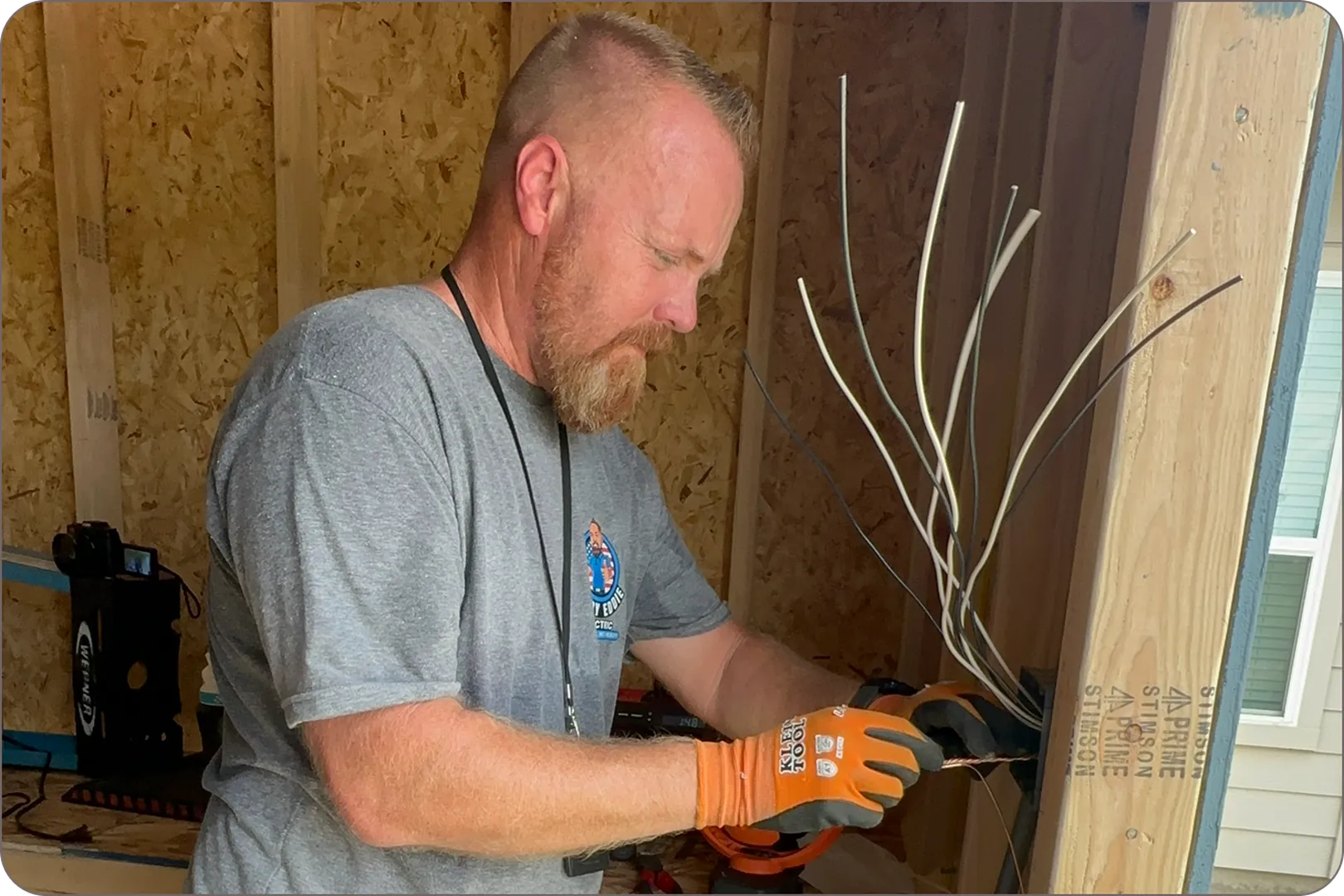 Eddie Burton carefully works on electrical wiring in a wooden shed, wearing protective gloves.