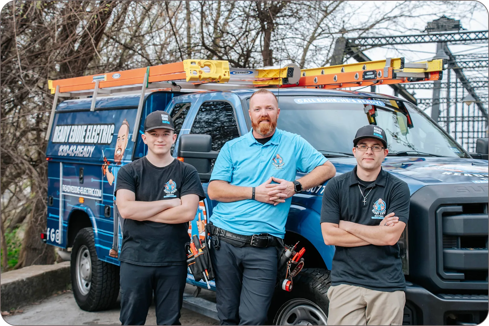 Eddie Burton and team stand by the blue company van in matching shirts.