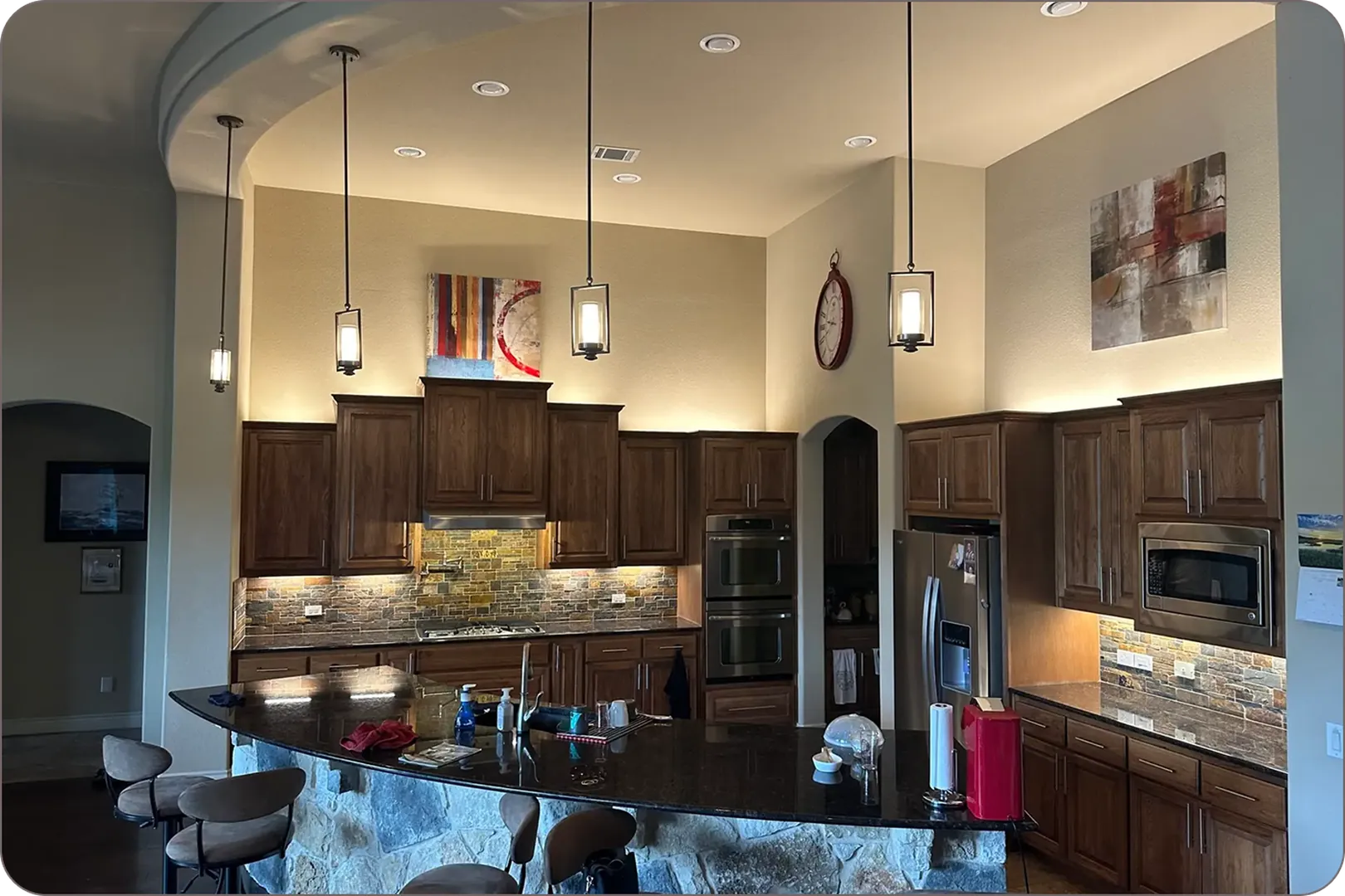 Large kitchen with dark wood cabinets, warm lighting, and modern appliances